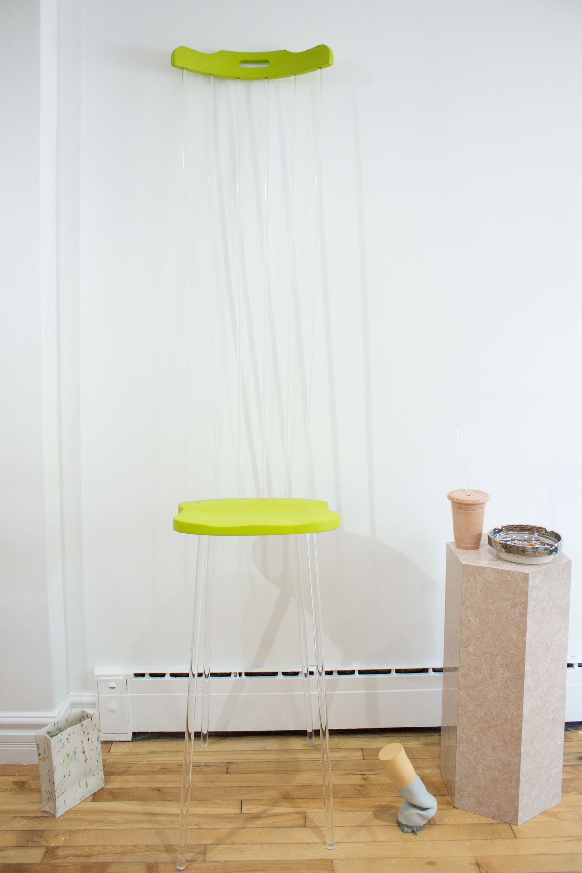 Comically tall lime green & clear lucite chair with speckled ceramic bag and giant ceramic cigarette butt